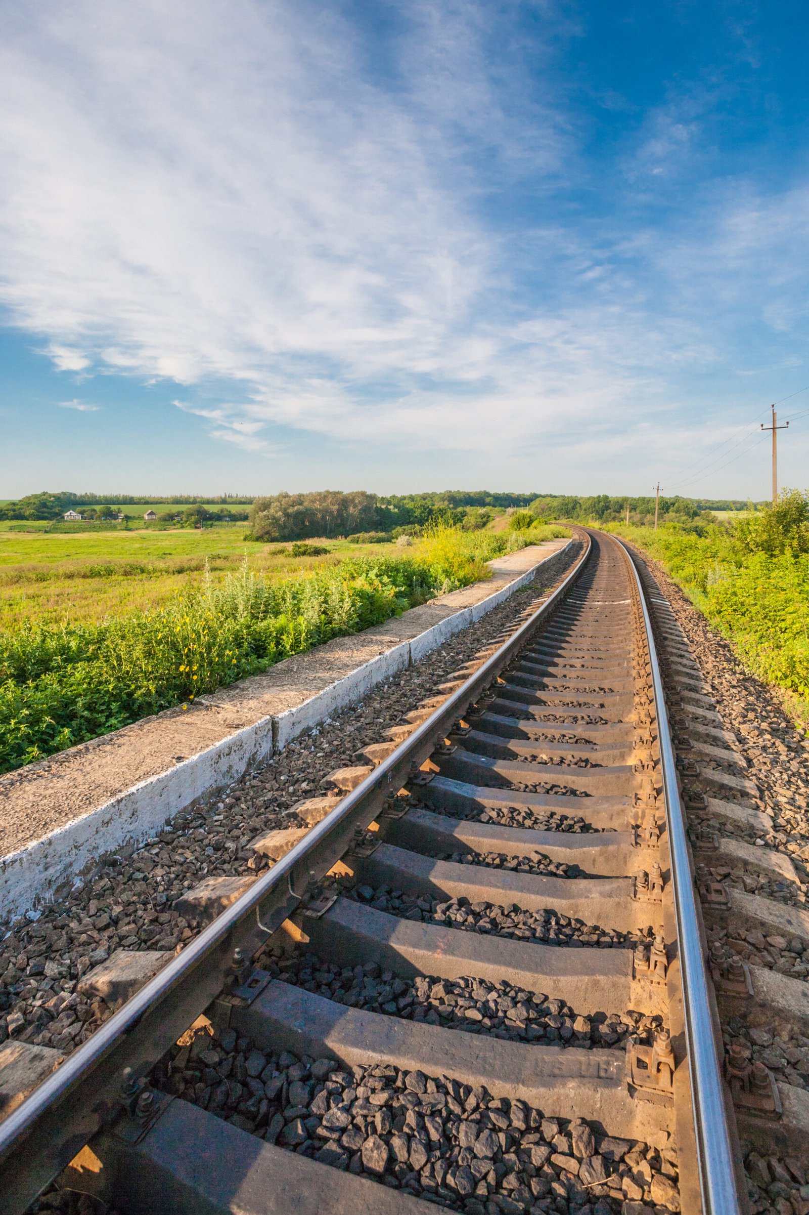 Railway station against beautiful sky at sunset. Industrial landscape with railroad, colorful cloudy blue sky. Railway sleepers. Railway junction. Travel background